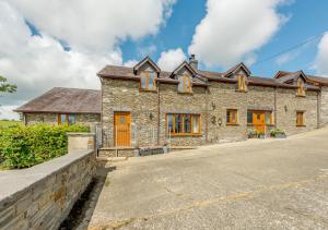 a large stone house with orange doors and windows at Beudy Bach in Silian