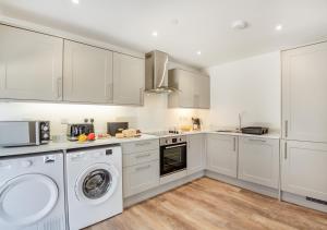a kitchen with white cabinets and a washer and dryer at Yr Hen Barlwr in Llanddyfnan