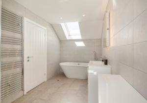 a white bathroom with a tub and a sink at Yr Hen Barlwr in Llanddyfnan