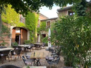 an outdoor patio with tables and chairs and plants at La Passiflore in Vergèze