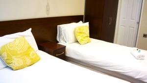 a bedroom with two beds with yellow and white pillows at OYO Oban Hotel in Eastbourne