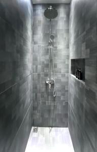 a bathroom with a shower with gray tiles at oxy suites G-01 at Shop House Meisterstadt Pollux Habibie in Batam Center