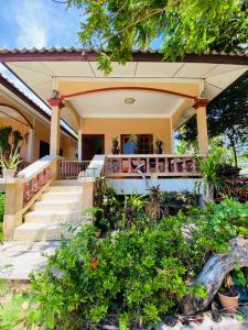 una casa con un porche con escaleras y plantas en Landscape beachfront bungalow in Rawai en Phuket