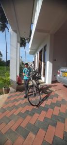 a boy standing with a bike in front of a house at Anuradhapura Kingdom View Resort in Anuradhapura
