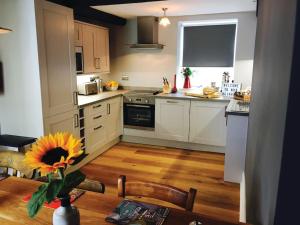 a kitchen with white cabinets and a table with a sunflower at No. 5 @ Ginhaus in Llandeilo