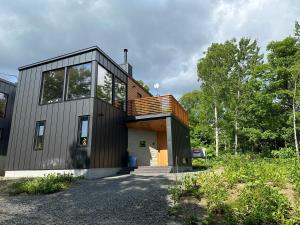 a house with a black facade with a wooden roof at Mizuki - walking distance to Rusutsu Resort in Rusutsu