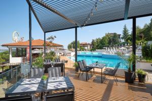 a deck with tables and chairs and a swimming pool at Santa Marina Holiday Village in Sozopol