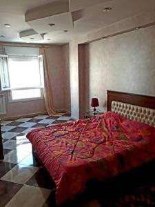 a bedroom with a bed with a red comforter at 2 minutes from Sheraton Oran. Come and relax here. in Oran