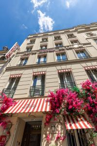 Um edifício com flores cor-de-rosa à frente. em Hôtel Marais de Launay em Paris