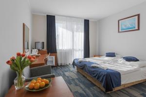 a hotel room with a bed and a table with a bowl of oranges at Pensjonat KoGa in Kołobrzeg