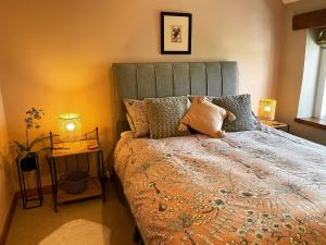 a bed in a bedroom with two lamps and a bed sidx sidx sidx at Honeysuckle Cottage in Longnor