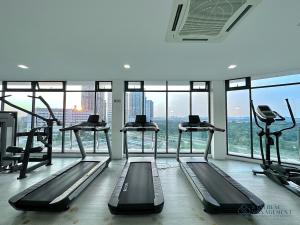 a gym with several tread machines in a room with windows at Elysia Park Residence Medini by Stayrene in Nusajaya
