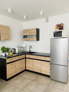 a kitchen with a stainless steel refrigerator and wooden cabinets at Gladiator Noclegi Zator lV Apartament in Zator