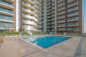 a swimming pool in front of a apartment building at Pacific 1BR at Azizi Samia Jebel Ali by Deluxe Holiday Homes in Dubai