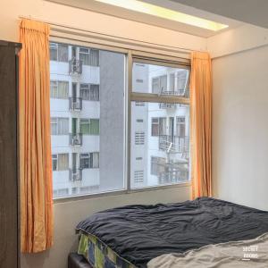 1 dormitorio con ventana y cortina naranja en The Jarrdin Apartement by Secret Rooms, en Bandung