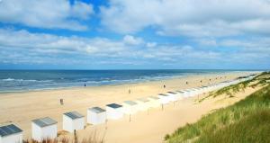 a beach with a row of umbrellas and the ocean at Breezy Beach Chalet in Petten
