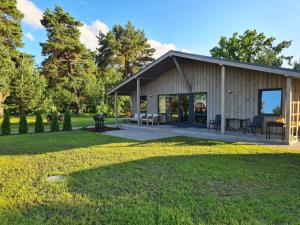 a barn house with a patio and a yard at Priedes in Engure