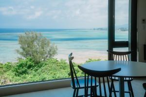 a table and chairs in a room with a view of the ocean at Blue Steak Wonder Yomitan in Yomitan