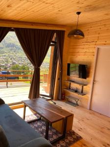 a living room with a table and a large window at Little Wood House Gergeti in Stepantsminda