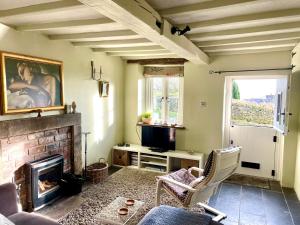 a living room with a fireplace and a tv at Honeysuckle Cottage in Longnor