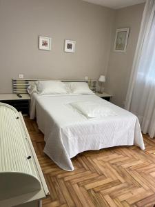 een slaapkamer met een wit bed en een houten vloer bij La de Mondi in Baiona