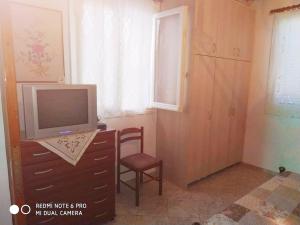 a bedroom with a tv on a dresser with a chair at Traditional Trikeri Escape House in Ayía Kiriakí