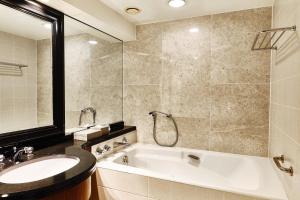 a bathroom with a tub and a sink and a mirror at InterContinental Tokyo Bay by IHG in Tokyo