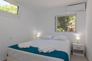 a white bedroom with a bed and a window at Angelana Beach Villa in Faliraki