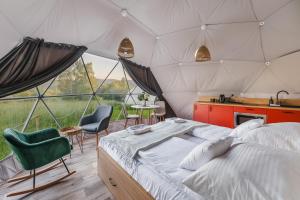 a bedroom with a bed and chairs in a tent at Biała Czapla Glamping z balią nad jeziorem czorsztyńskim in Maniowy