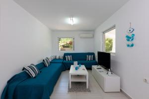 a living room with a blue couch and a tv at Angelana Beach Villa in Faliraki