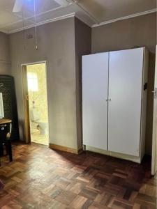 a room with a large white cabinet and a bathroom at Nomacurvy guest house in Roodepoort