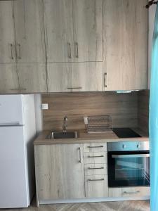 a kitchen with wooden cabinets and a sink and a refrigerator at Apartment Nikolay in Nea Potidaea