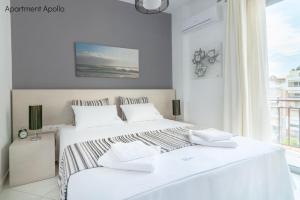 a white bedroom with two beds and a window at Apollo & Artemis by Heloni Apartments in Athens