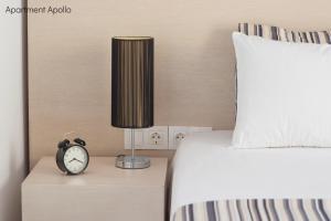 a bed with a lamp and a clock on a night stand at Apollo & Artemis by Heloni Apartments in Athens