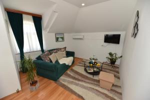 sala de estar con silla verde y TV en Apartmani Lucija en Ludbreg