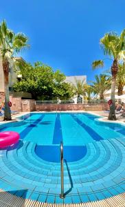 a swimming pool with palm trees and a blue at Malia Semiramis by Estia in Malia