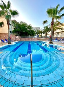 a large swimming pool with palm trees in the background at Malia Semiramis by Estia in Malia