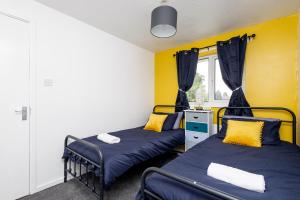 two beds in a room with yellow walls at Gorgeous Grange Fields Home - Free Parking, Self Check-in, High Speed Wi-fi, Excellent City Centre Access - Contractors Welcome in Leeds
