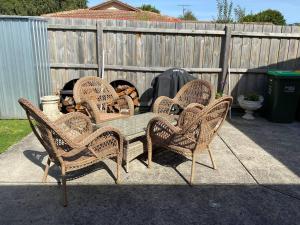 vier rieten stoelen en een tafel op een patio bij House of Hearts in Wonthaggi