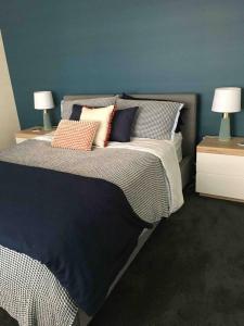a bedroom with a bed with pillows and two lamps at House of Hearts in Wonthaggi