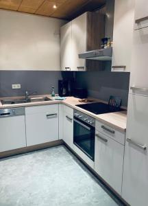 a kitchen with white cabinets and a stove top oven at Naturstrand Apartment - 86m² - 4 Betten - Parkplatz in Hagermarsch