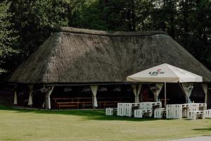 a group of white chairs and an umbrella at Dom Wypoczynkowy "Pod Strzechą" w Giewartowie in Giewartów