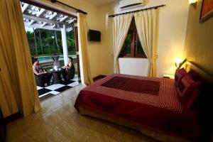 a bedroom with a bed and two people sitting on a patio at Villa Velmarie Yoga and Ayurveda house all inclusive in Beruwala