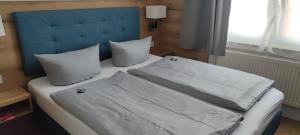 a bed with a blue headboard and white sheets and pillows at Hotel Haus Borkum in Borkum