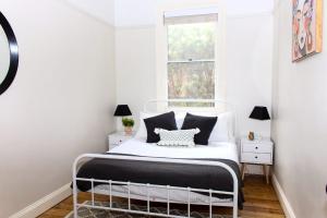 a white bedroom with a bed with black and white pillows at Family Retreat East Tamworth in Tamworth