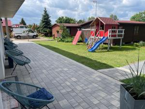 a playground with a slide and chairs in a yard at Urocze Apartamenty LOFT przy Molo in Chłopy