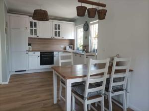 a kitchen with white cabinets and a wooden table and chairs at Landidyll 
