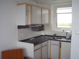 a small kitchen with a sink and a window at Tief 10 Wohnung 408 in Wangerland