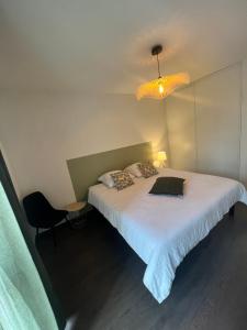 - une chambre avec un grand lit blanc et un lustre dans l'établissement T2 cosy Ajaccio, à Ajaccio