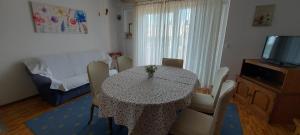 a dining room with a table with chairs and a television at Apartman Franelić Banjol in Banjol
